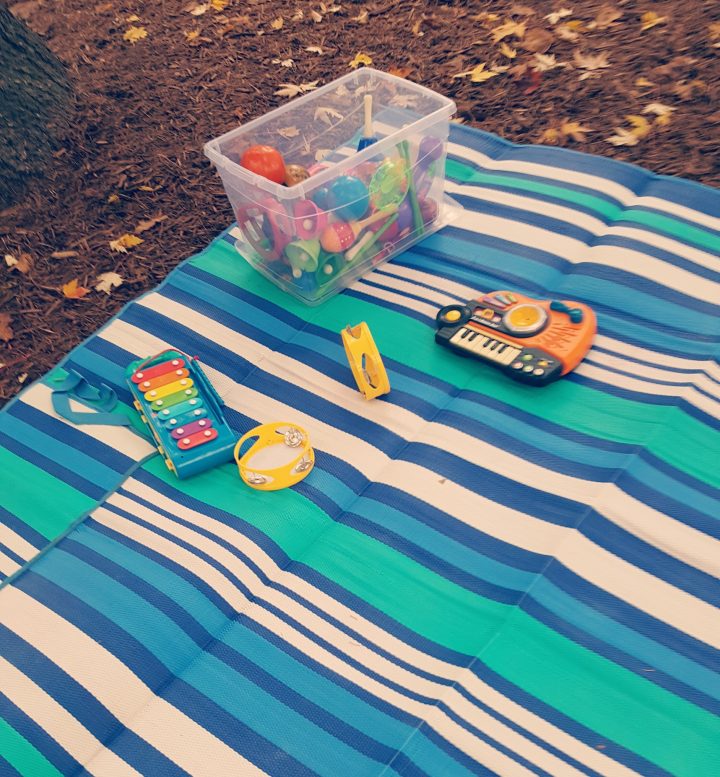 outdoor teaching ideas shows a blanket with a bin of musical instruments for kids.