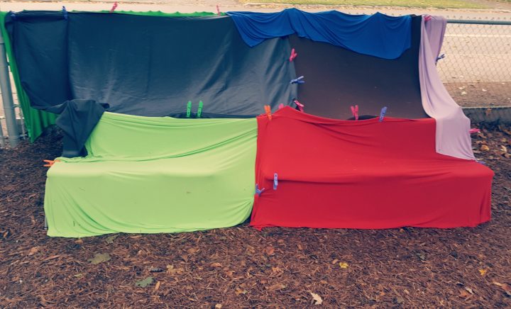 outdoor play shows a haunted house outside made from blankets attached to a fence.