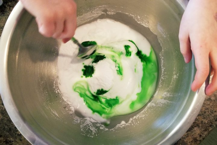 science experiment shows a child stirring a bowl of white with swirls of green