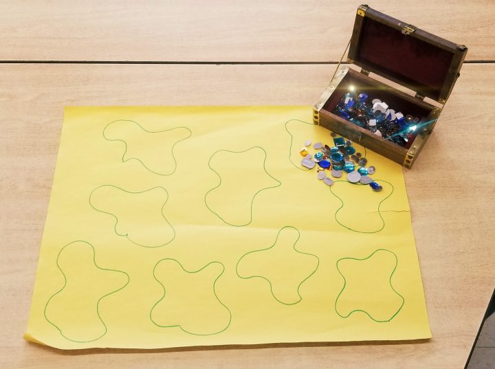 kindergarten math activities shows a small treasure chest with gems and a large sheet with blobs drawn on it.
