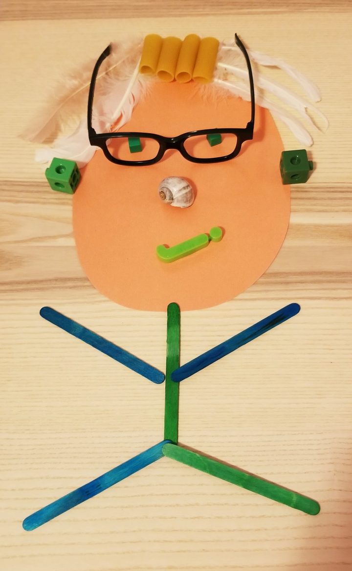 kids art activity shows a person made from glasses, pasta, feathers, popsicle sticks and other random object.