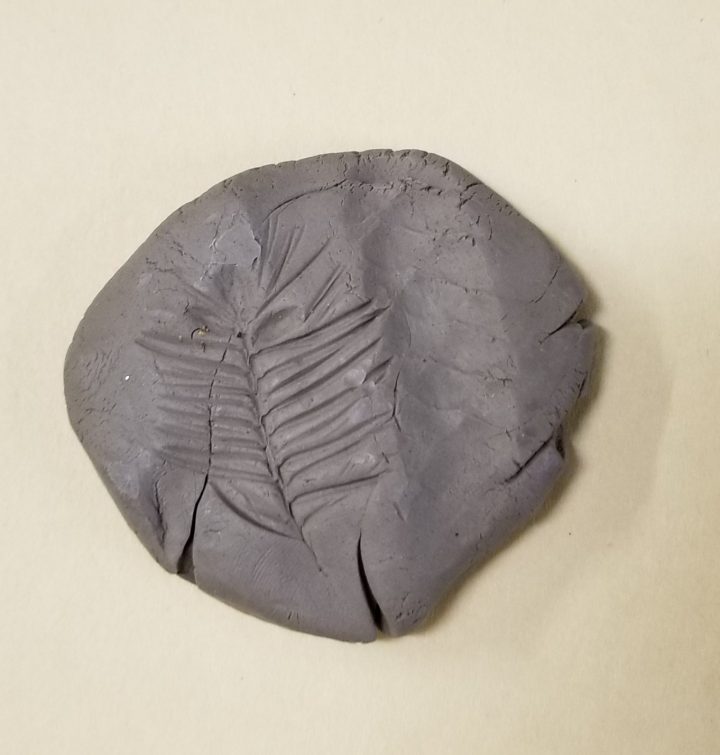 easy clay projects shows a ball of clay with a leaf print on it.
