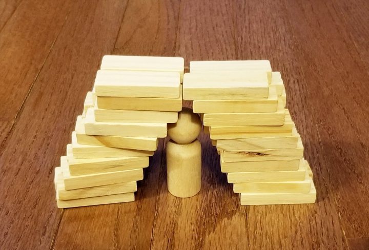 stem activity for kids shows a shelter for a wooden person made from wooden blocks.