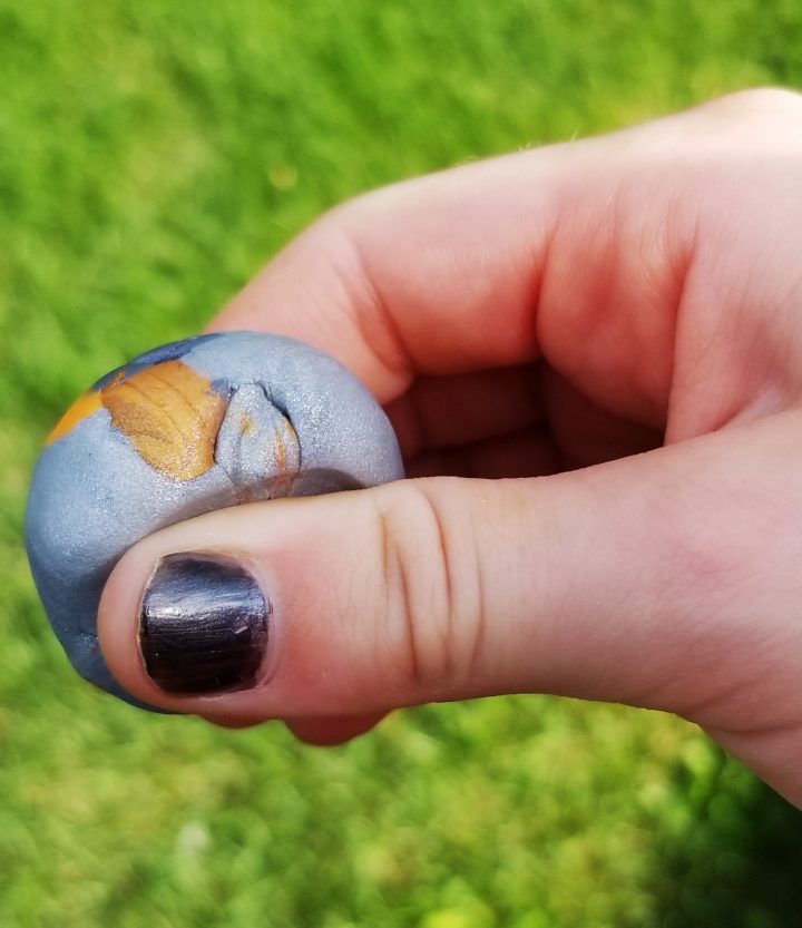 mindfulness art shows a child holding a silver and gold polymer clay stone.