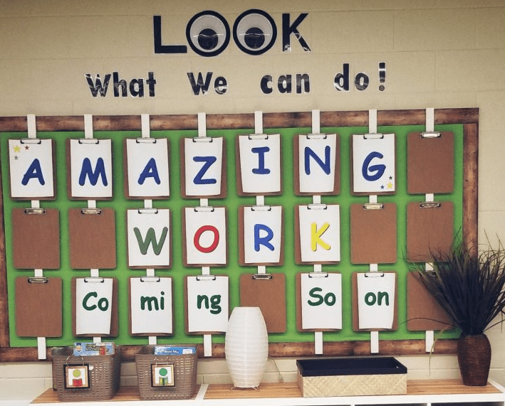 classroom set up shows a bulliten board with clipboards and what says "Look what we can do.  amazing work coming soon"