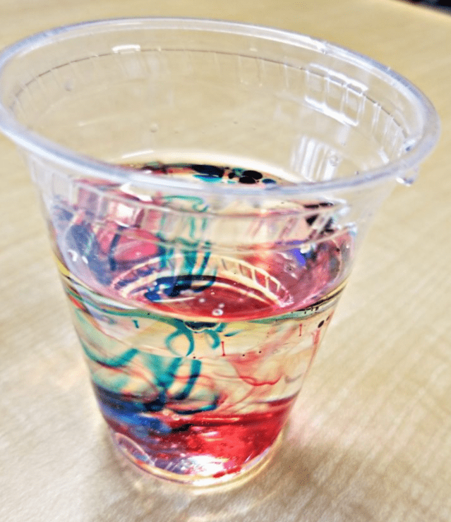 new years eve party ideas and a clear cup with blue and red color swirling through water.
