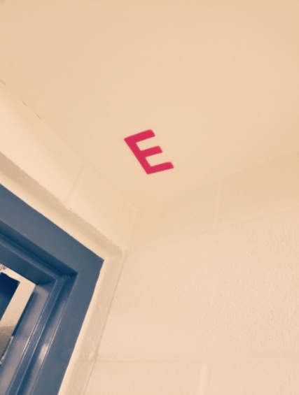 letter games shows the letter E stuck to the ceiling of a school. 