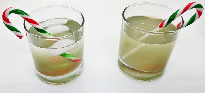 Christmas science experiment shows two cups with candy canes and foggy water that the canes have dissolved in.
