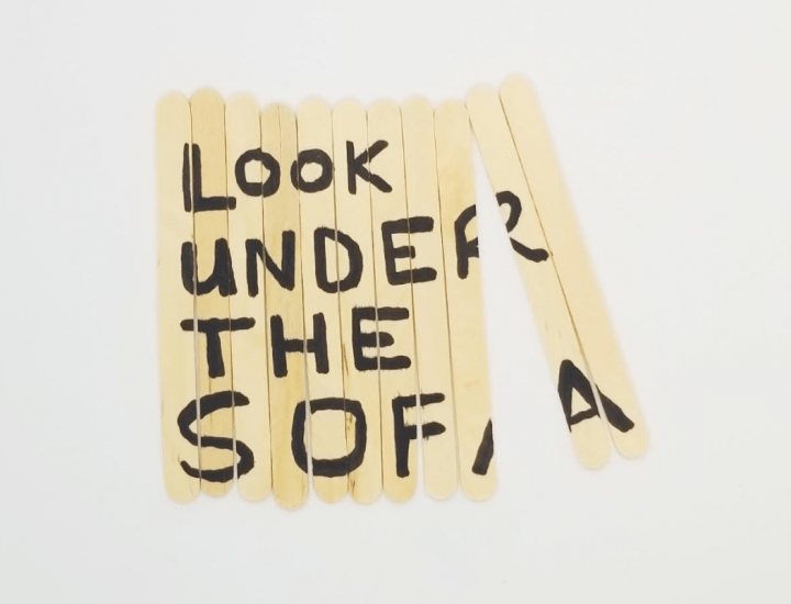 escape room shows popsicle sticks with the words look under the sofa.