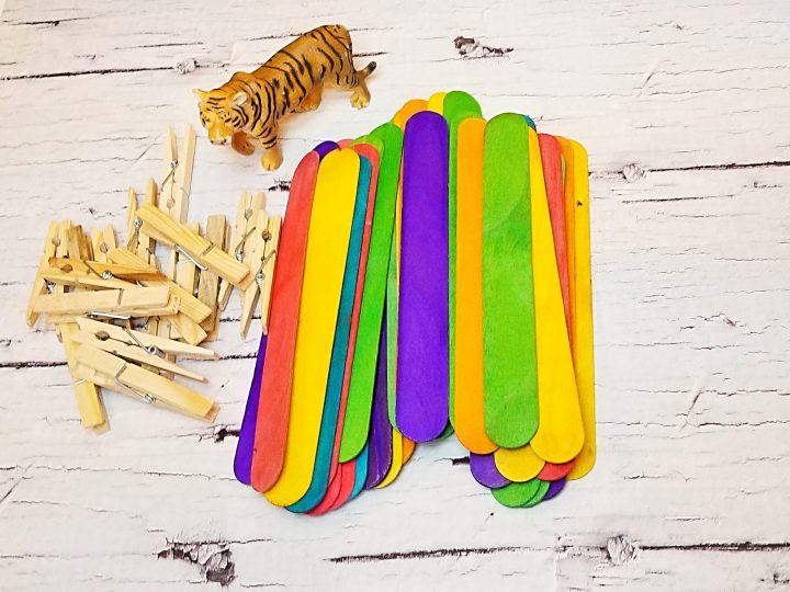 STEM for kids shows a stack of colorful jumbo popsicle sticks, a toy lion and clothes pins.