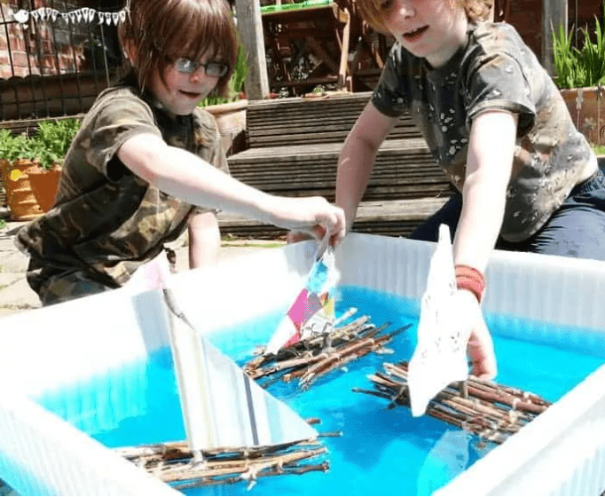 boat building shows children with a stick boat.