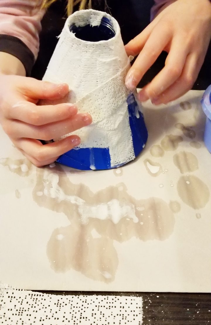 DIY volcano shows a child creating a volcano with plaster.