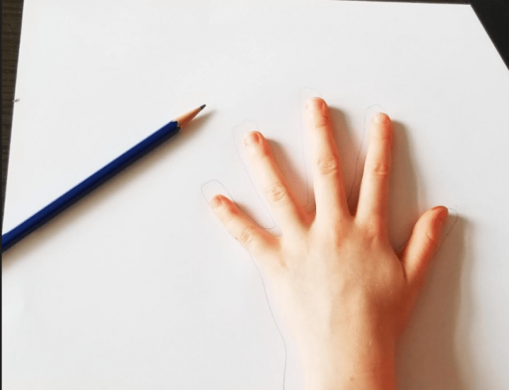 art ideas shows a child holding their hand to a white page and a pencil beside them.
