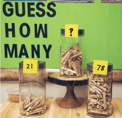 number talks shows three jars filled with a different number of clothes pins and a sign on the wall that says guess how many.