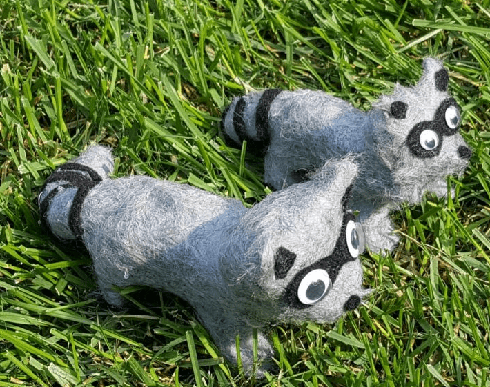 clay animals shows two racoons in the grass made from clay.