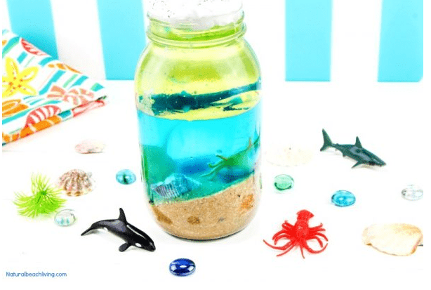 science experiments for kids shows a beach theme image with a jar with sand, blue water and oil.