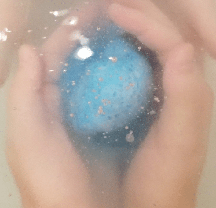 diy escape room shows a persons hands holding a blue bath bomb under water