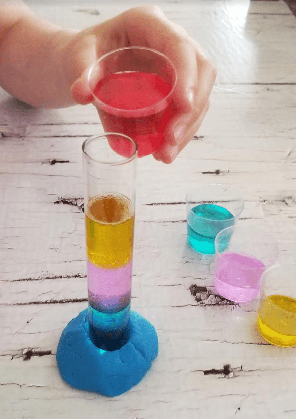 chemistry experiment shows a child pouring red liquid into a test tube.