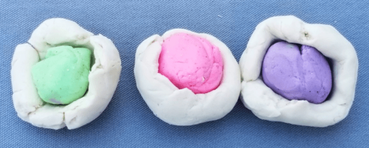 first day of school activity shows three ball of play dough with green, pink and purple balls of dough surrounded by white dough.