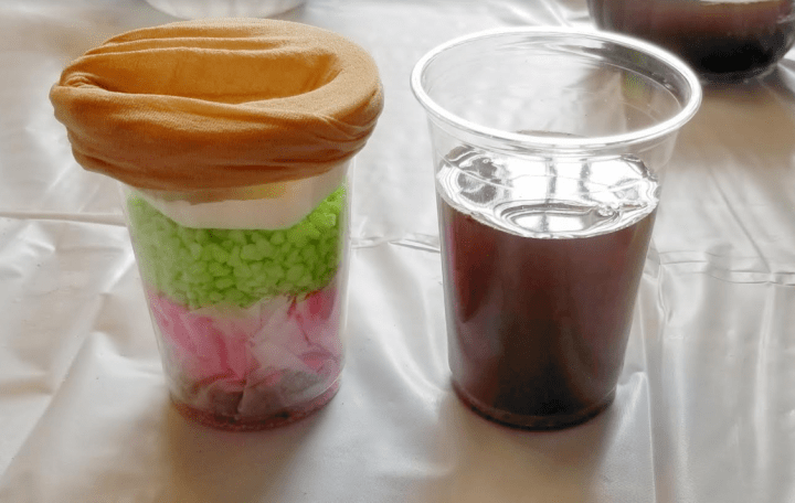 clean water experiment shows two cups.  One with dirty muddy water and the other with layers of filtration.
