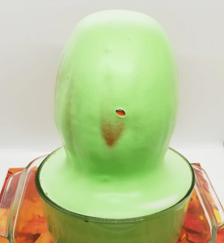 science experiment for kids shows a pumpkin with green foam running out of it.