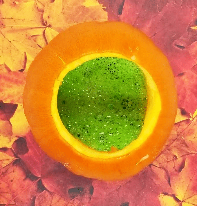 science experiment for kids shows a top view of a pumpkin with green bubbles inside.