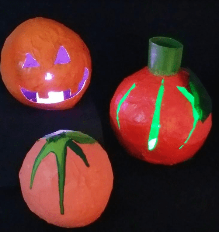 Halloween craft  for kids shows three paper mache pumpkins with tea lights.