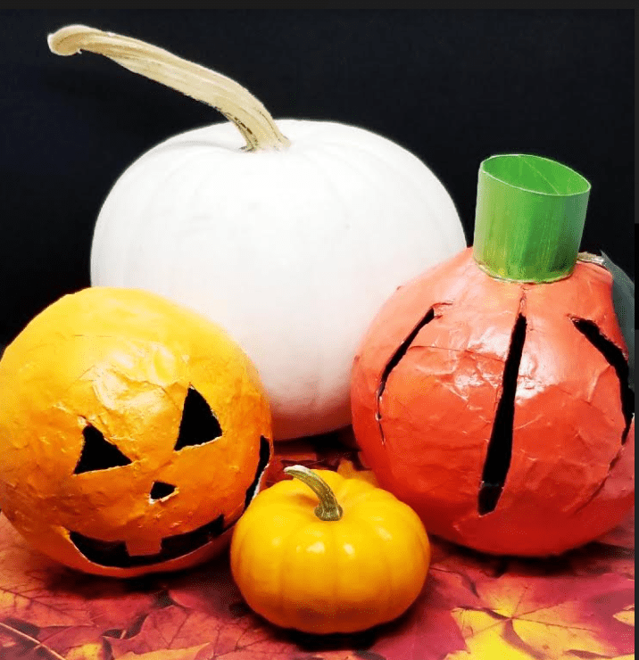 Halloween craft  for kids shows two paper mache pumpkins and two real pumpkins.
