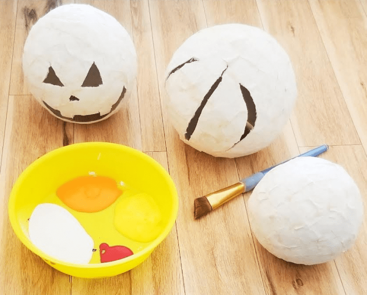Halloween craft  for kids shows paper mache pumpkins ready to be painted.