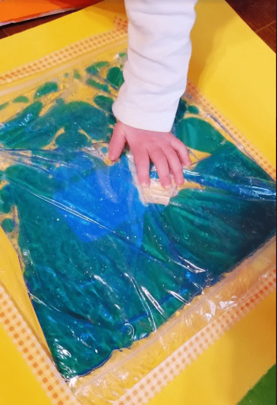 sensory play shows a child touching a clear bag with a blue liquid in it
