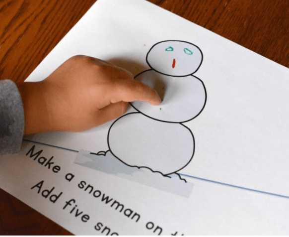 math worksheets for kindergarten shows a child pointing to a snowman in a book.