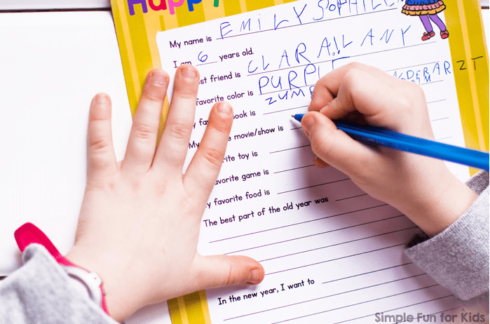 new years eve activities for families. A young child's hand is holding a pen and printing in answers on a sheet.