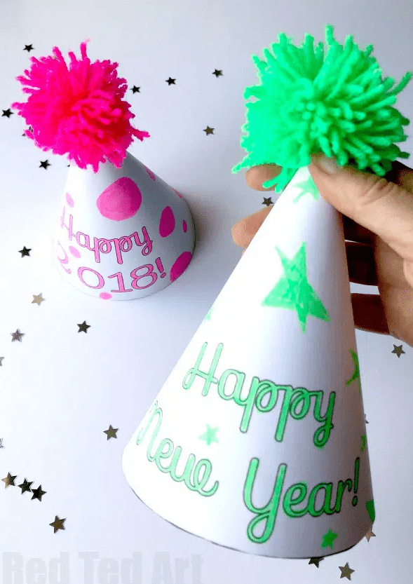 new years eve ideas for families and a pink and yellow colored happy new year printable hat with a pompom on the top of each made from yarn.