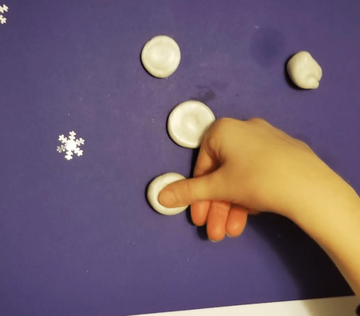 clay crafts shows a child pushing their thumb print into a white clay ball.
