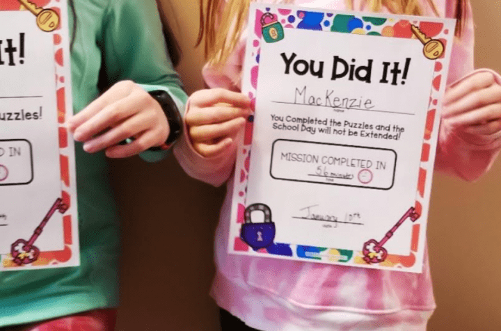 A child is holding their escape room certificate.