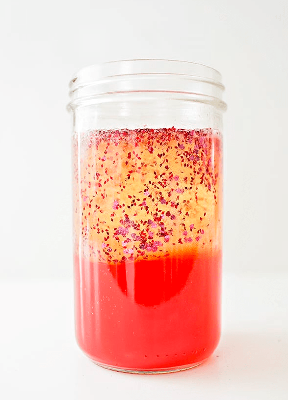 valentines day stem activities image shows a clear jar with the bottom half solid red and the other half is yellowish with sparkles