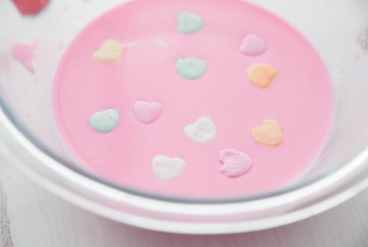 valentines day stem activities for kids a clear bowl with pink liquid and candy hearts floating in it