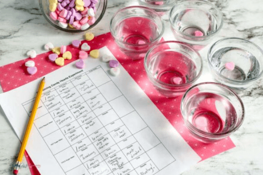 Valentines day stem activities the image shows small bowls with with candy hearts and a worksheet.