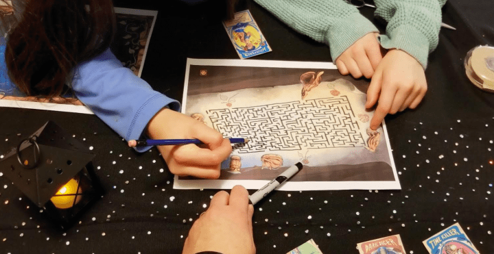 escape room puzzles with three people using pencils to solve a maze