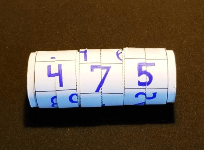 Puzzle idea shows 6 strips of paper around a roll with numbers