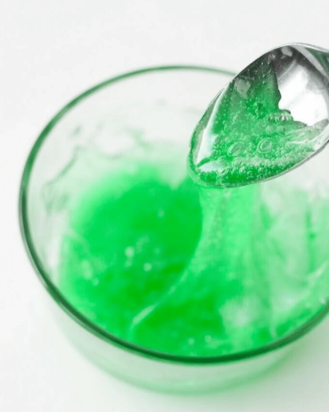 science experiments for kids shows a spoon scooping a sticky green liquid up