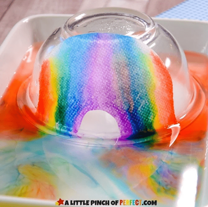 science experiments for kids shows a rainbow on paper towel creating an arch with a glass bowl over it