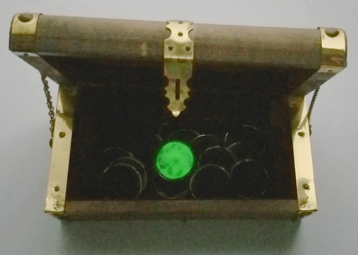 escape room puzzle shows a treasure box with coins and one glowing coin.