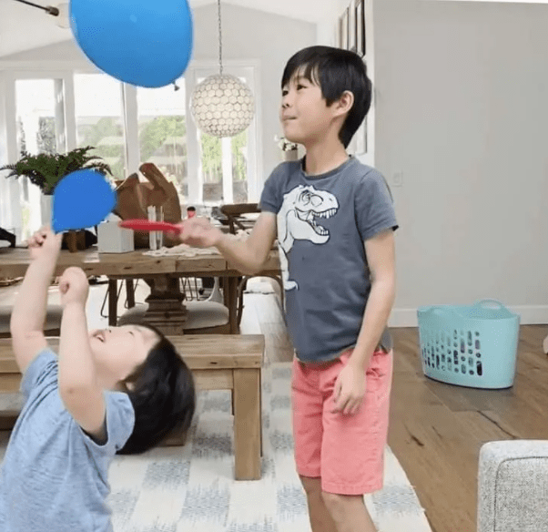 gym games for kids shows two children bouncing a blue balloon.