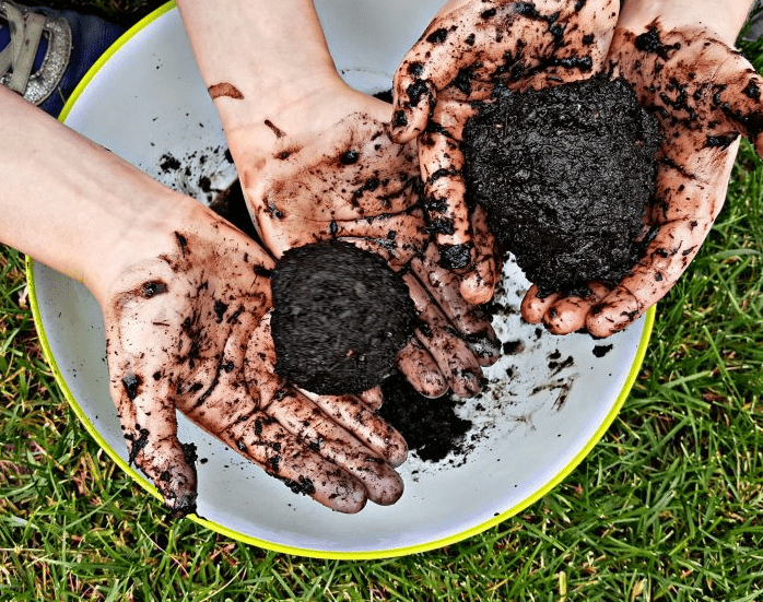spring outdoor learning activities shows two little hands holding a mud ball