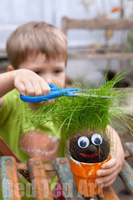 spring stem activities shows a child cutting the hair on a grass head craft