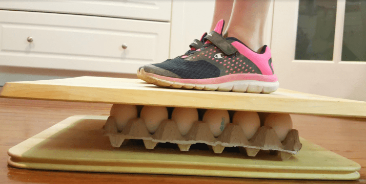 summer science experiments shows a child standing on a dozen eggs