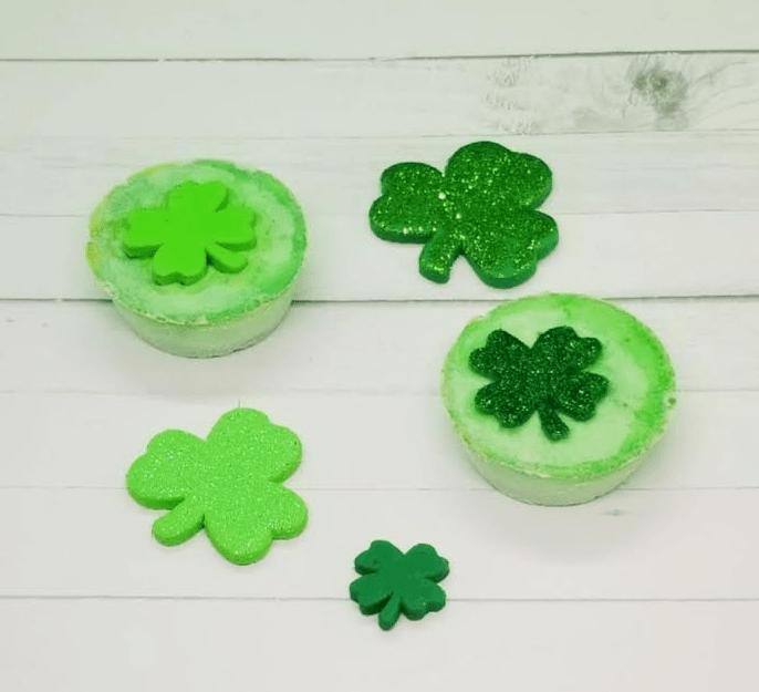 st patricks day science experiment shows two baking soda pucks surrounded by green shamrocks.