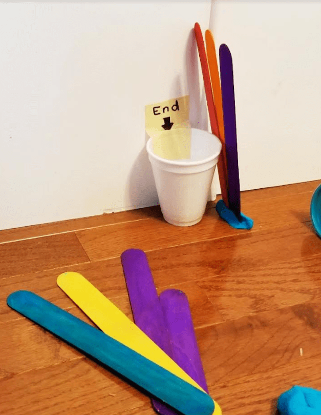 STEM activities the image shows tongue depressors, a cup with tape on it that says end and blue play dough