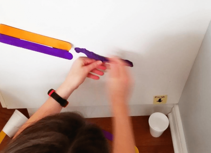 STEM challenge shows a child attaching playdough to a wall and popsicle sticks